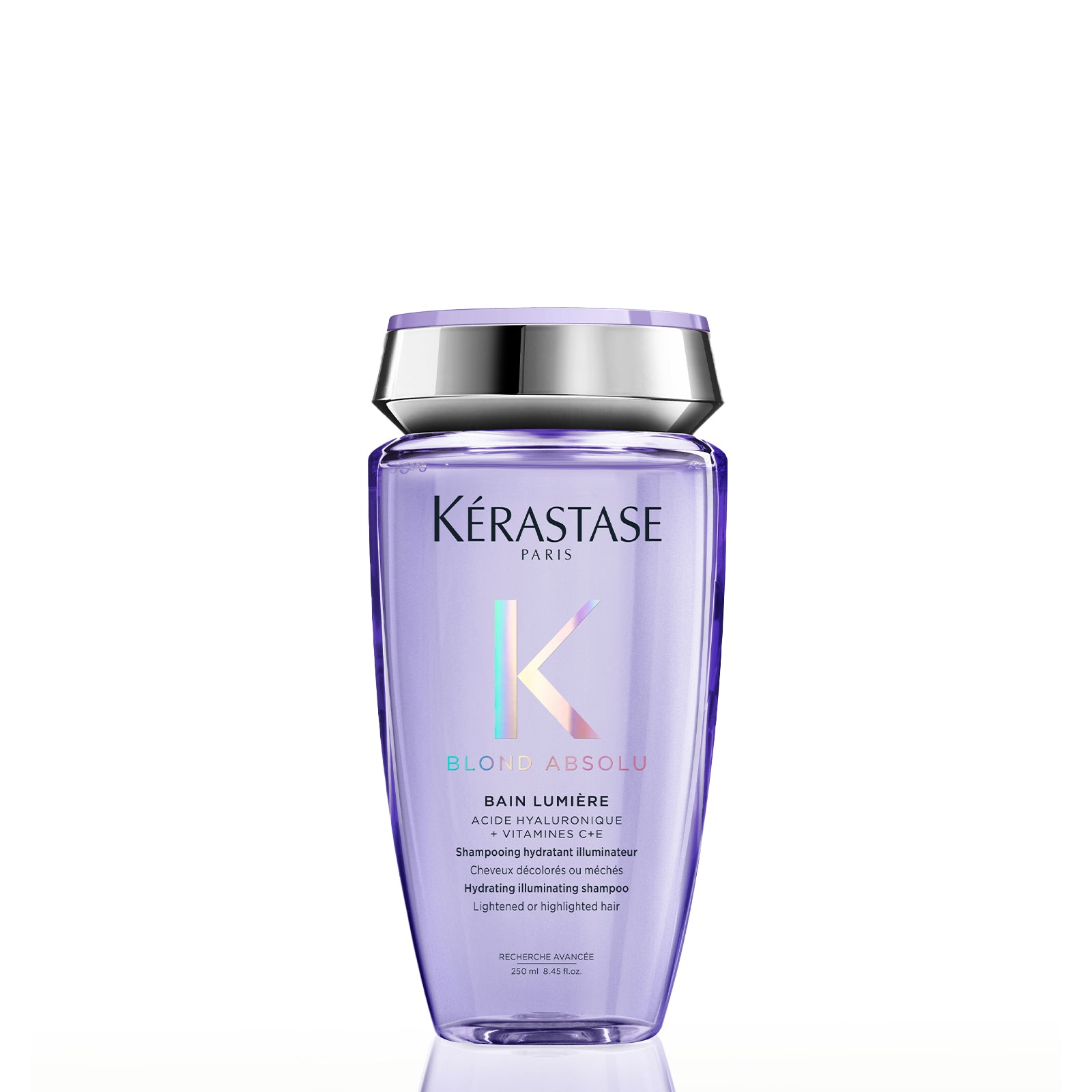 Image of Kérastase Paris Blon Absolu Bain Lumère shampoo bottle in a translucent light purple color with a metallic silver cap, shown on a white background with a soft reflection.