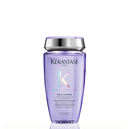 Kérastase Paris Blon Absolu Bain Lumère shampoo bottle in a translucent light purple color with a metallic silver cap, shown on a white background with a soft reflection.
