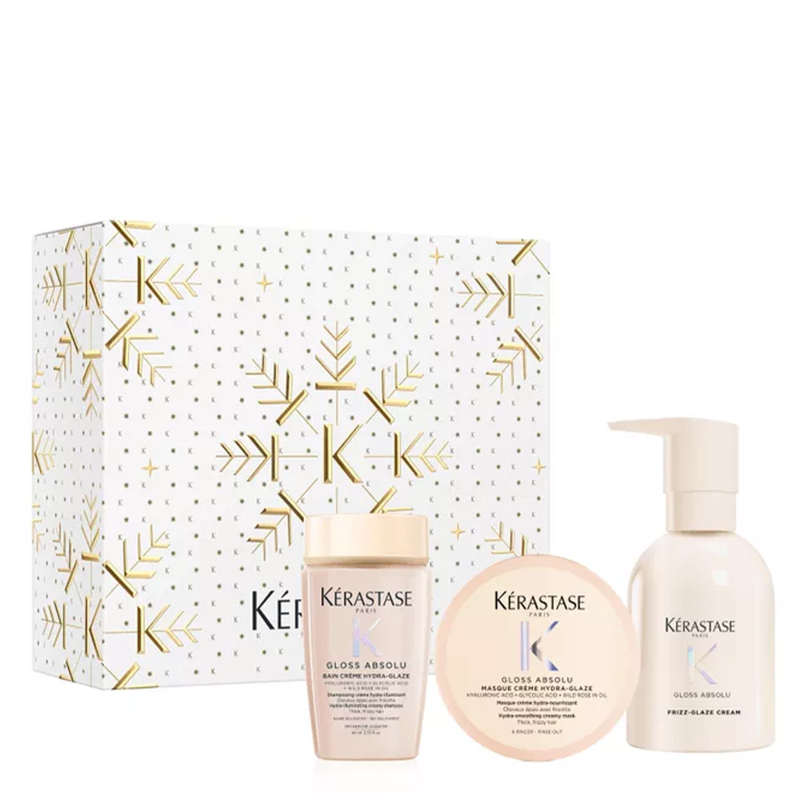 Image of Kérastase haircare gift set featuring a white box with gold snowflake and dot patterns, alongside a Gloss Absolu bottle, a Shine Absolu jar, and a Pump Absolu cream bottle, all on a white background.