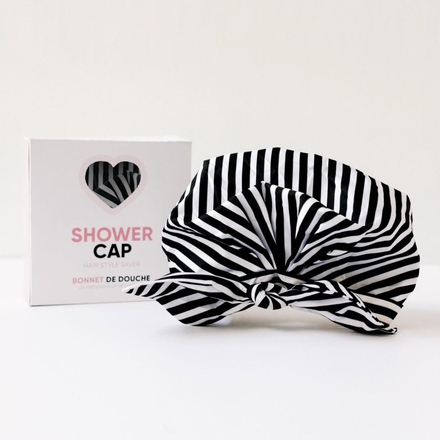 A black and white Pommeshell striped shower cap displayed next to its packaging box.