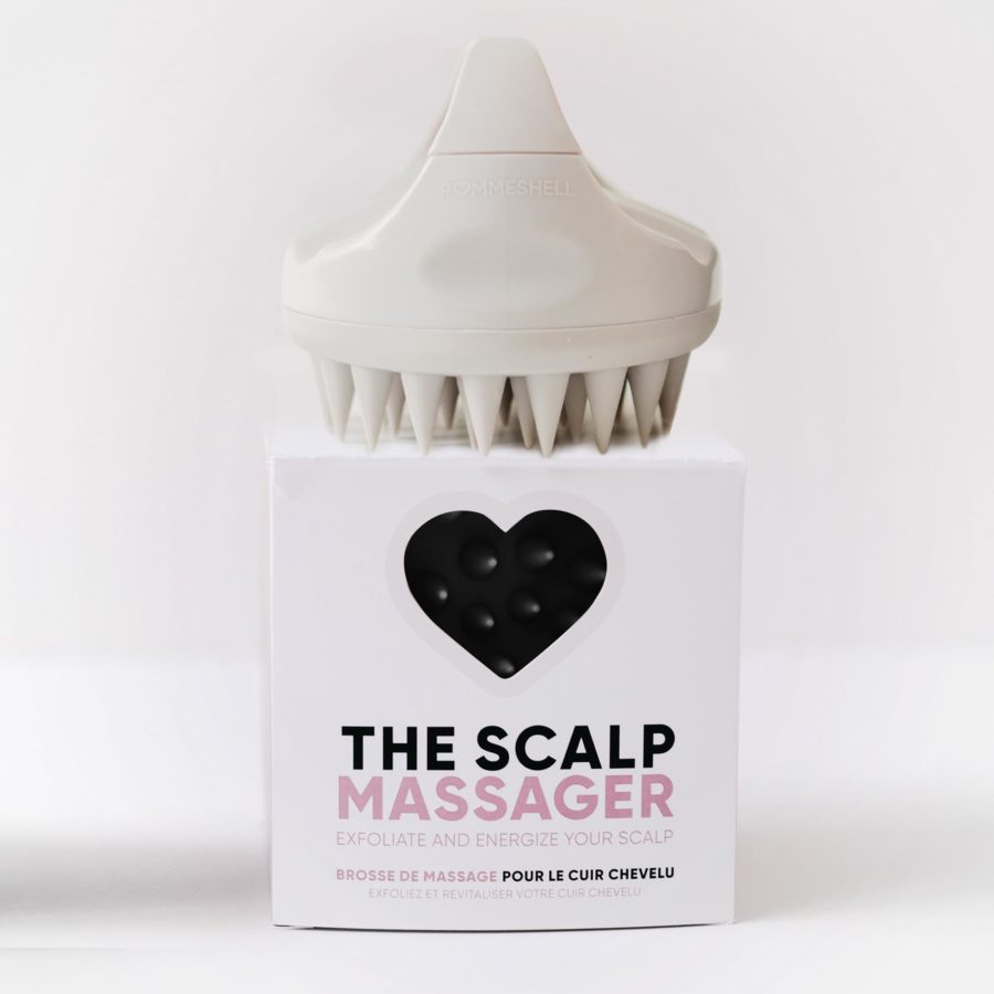 A scalp massager sits atop its packaging, which is labeled "the scalp massager".