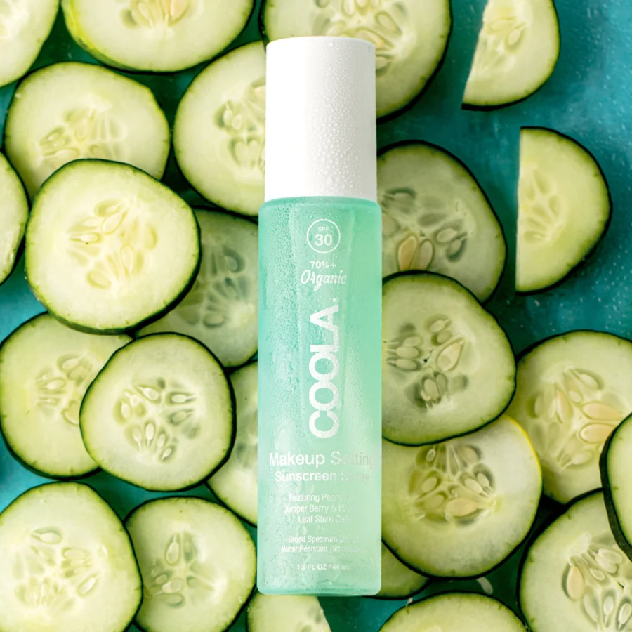 an image of the coola makeup setting spray on a background of cucumber slices.