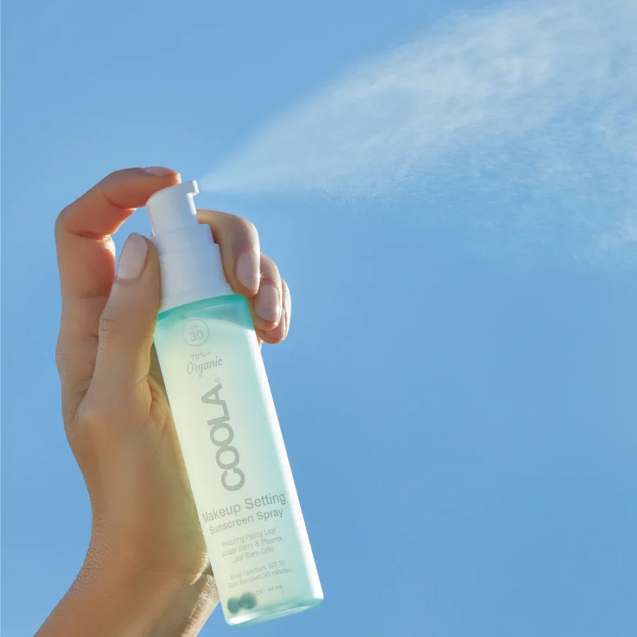 an image of the coola makeup setting spray being misted on a blue background.